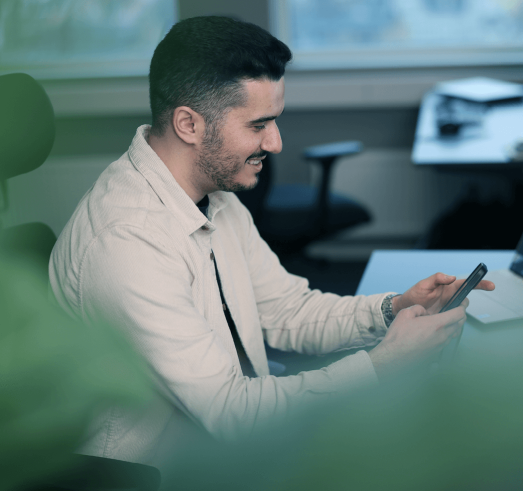 Foto av en leende man som tittar p&aring; telefonen.