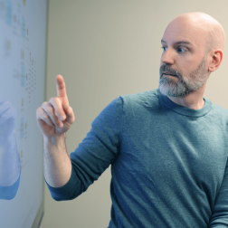 Ett foto av en man som sitter framf&ouml;r en tv-sk&auml;rm och pekar p&aring; processer.