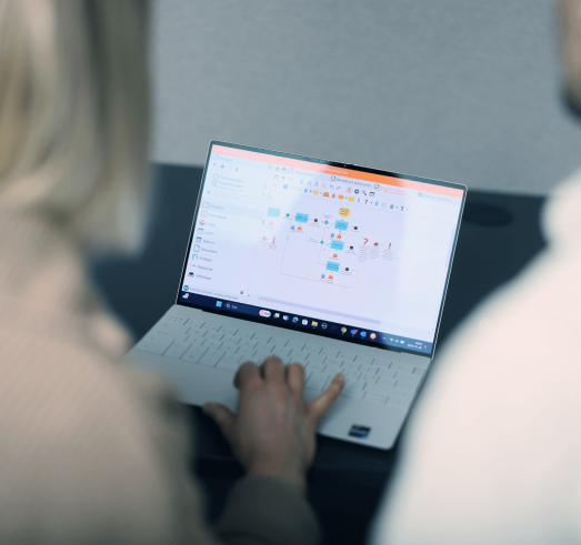 Ett foto av en kvinna som arbetar p&aring; en laptop d&auml;r hon kartl&auml;gger en process i 2c8 Apps.